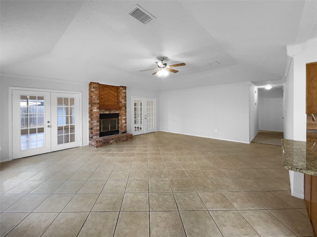 unfurnished living room featuring a brick fireplace, light tile patterned floors, and french doors