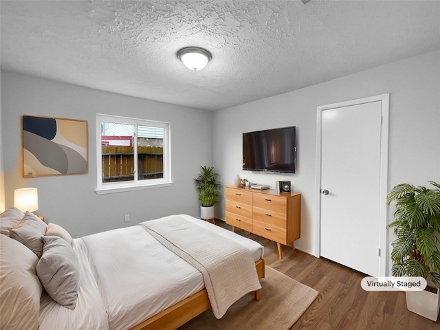 bedroom with dark hardwood / wood-style floors and a textured ceiling