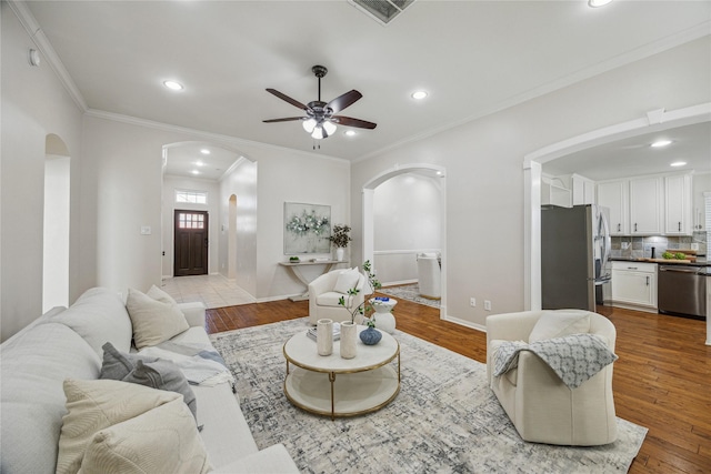 living room featuring ceiling fan, ornamental molding, and wood-type flooring