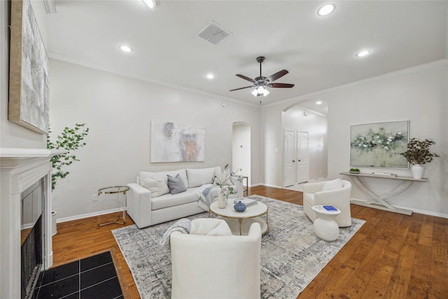 living room with crown molding, dark wood-type flooring, and ceiling fan