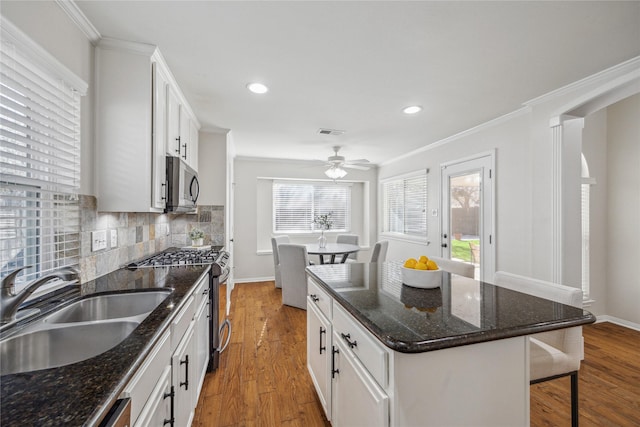 kitchen featuring a kitchen island, appliances with stainless steel finishes, sink, white cabinets, and crown molding