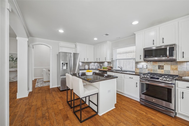 kitchen with stainless steel appliances, white cabinetry, a kitchen island, and a kitchen breakfast bar