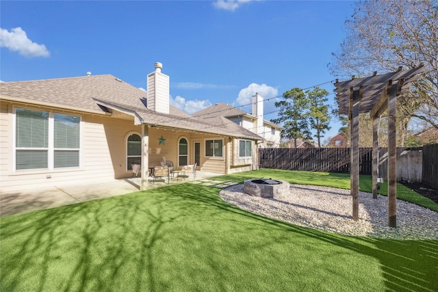 rear view of property with a fire pit, a patio area, and a lawn