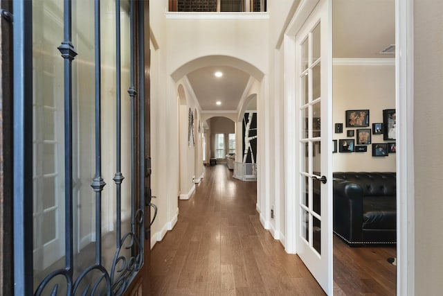 foyer featuring arched walkways, wood finished floors, crown molding, and french doors