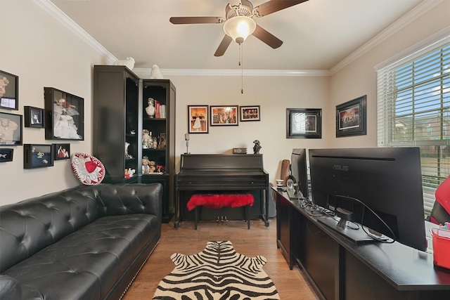 living area with ornamental molding, light wood finished floors, and a ceiling fan