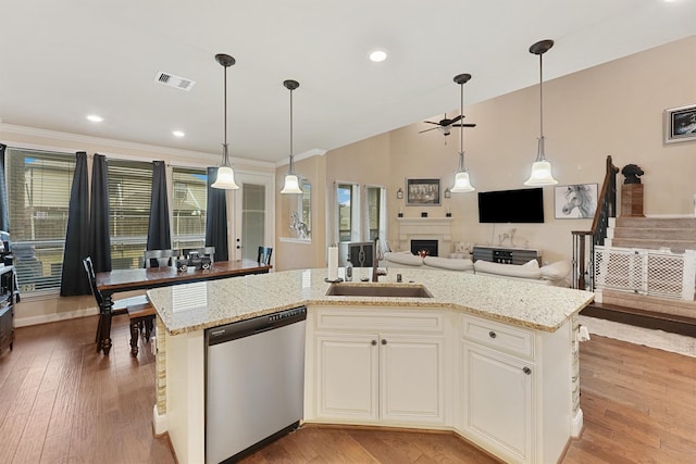 kitchen featuring light hardwood / wood-style floors, stainless steel dishwasher, light stone countertops, and a kitchen island with sink