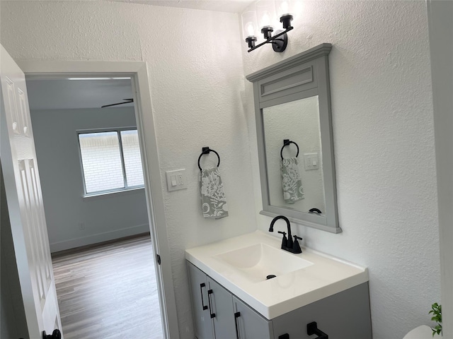 bathroom featuring a textured wall, wood finished floors, vanity, and baseboards