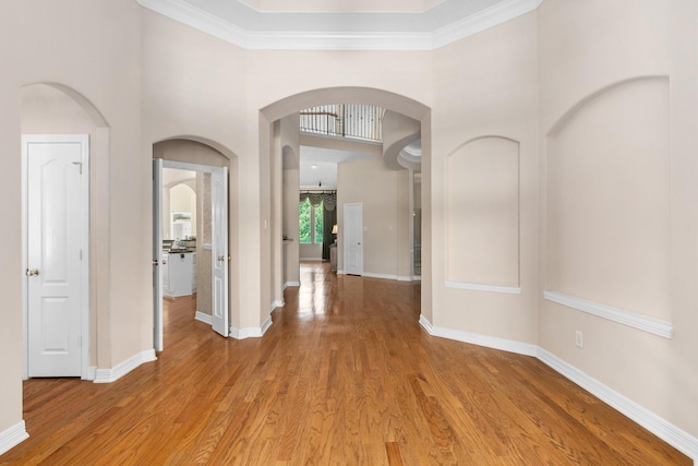 hallway featuring hardwood / wood-style flooring, ornamental molding, and a towering ceiling