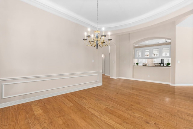 unfurnished room featuring hardwood / wood-style flooring, ornamental molding, a tray ceiling, and a chandelier