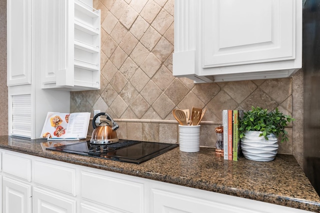 kitchen with white cabinetry, black electric stovetop, backsplash, and dark stone counters