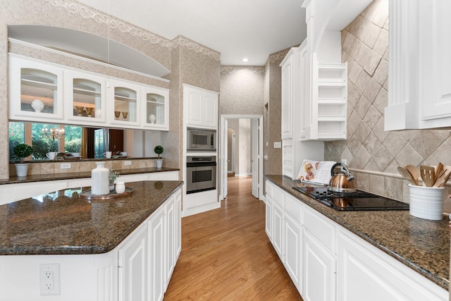 kitchen with stainless steel appliances, white cabinetry, light hardwood / wood-style flooring, and dark stone counters