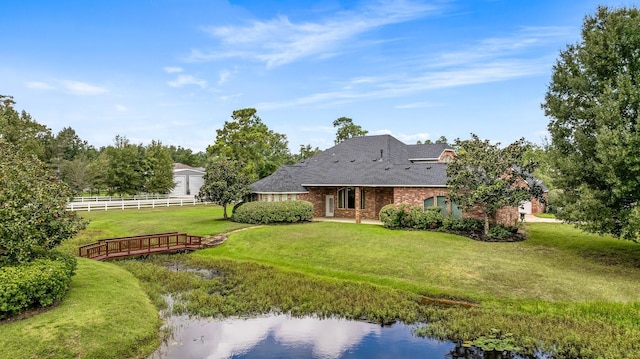 rear view of house featuring a water view and a lawn