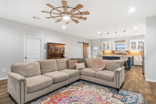 living room featuring ceiling fan, a barn door, and hardwood / wood-style floors