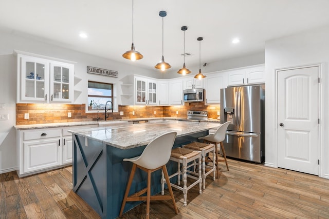 kitchen with sink, appliances with stainless steel finishes, a center island, light stone counters, and white cabinets