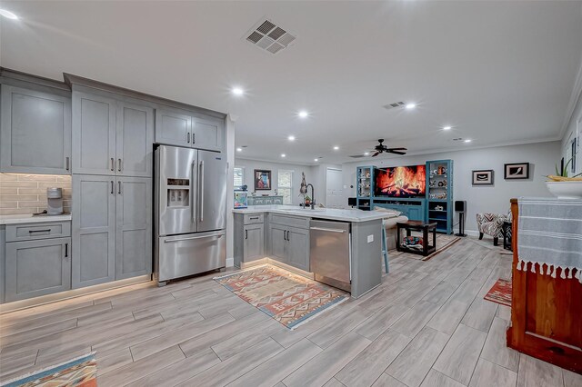 kitchen with gray cabinetry, sink, kitchen peninsula, and appliances with stainless steel finishes