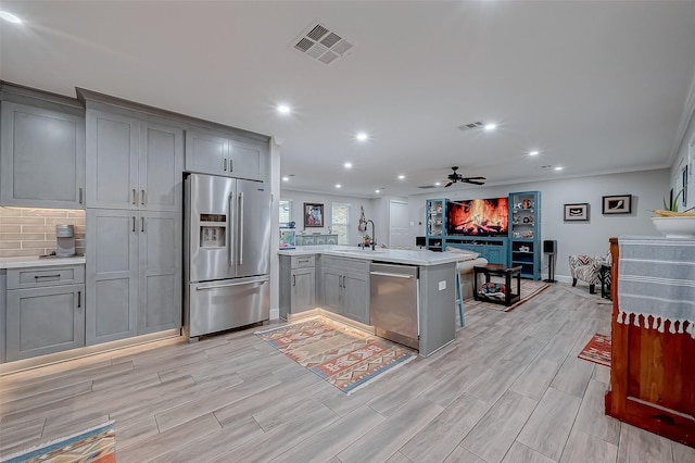 kitchen featuring stainless steel appliances, gray cabinets, kitchen peninsula, and sink