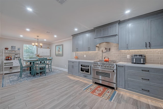 kitchen with high end stainless steel range oven, decorative light fixtures, decorative backsplash, and gray cabinetry