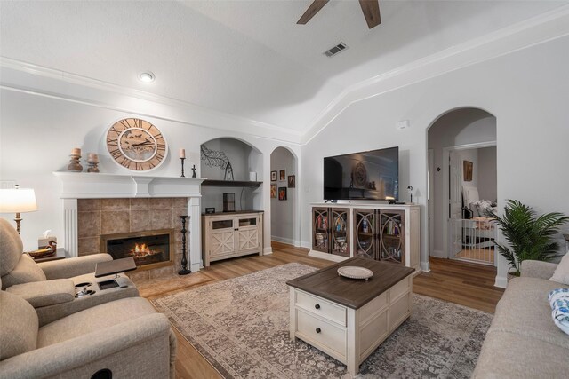 living room featuring vaulted ceiling, ceiling fan, a fireplace, and light hardwood / wood-style flooring