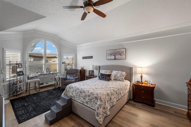 bedroom with ceiling fan, light hardwood / wood-style floors, vaulted ceiling, and a textured ceiling