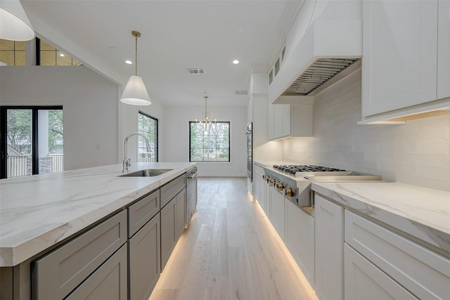 kitchen featuring white cabinetry, premium range hood, sink, and stainless steel gas cooktop