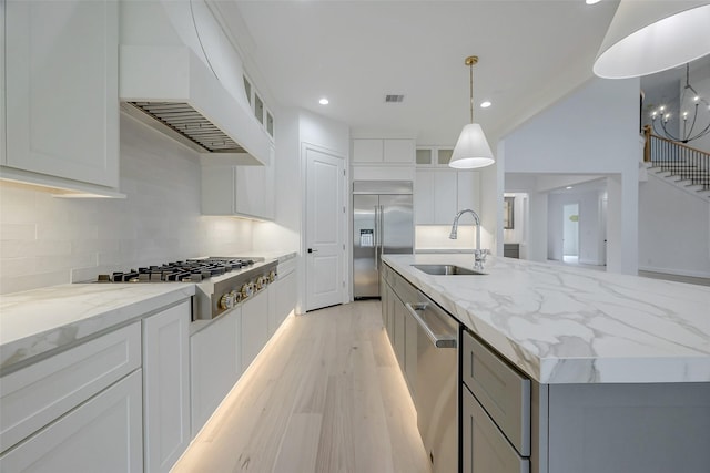 kitchen featuring sink, a center island with sink, custom range hood, pendant lighting, and stainless steel appliances