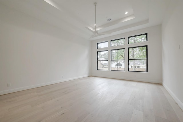 empty room featuring ceiling fan, a raised ceiling, and light hardwood / wood-style flooring