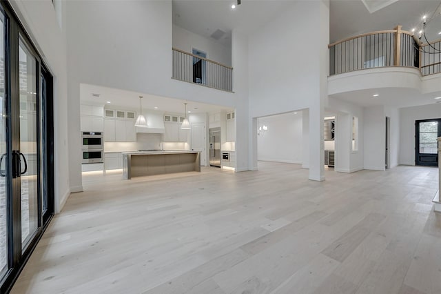 unfurnished living room with light hardwood / wood-style flooring and a notable chandelier