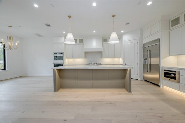 kitchen with white cabinets, stainless steel appliances, premium range hood, and a center island with sink