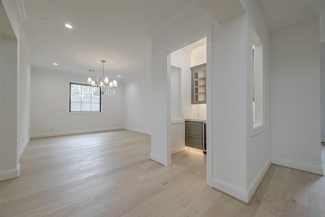 empty room featuring ornamental molding, a notable chandelier, and light hardwood / wood-style flooring