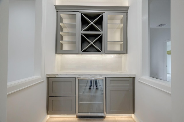 bar with beverage cooler, gray cabinets, and decorative backsplash