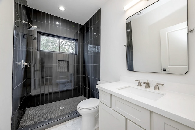 bathroom with vanity, toilet, and tiled shower