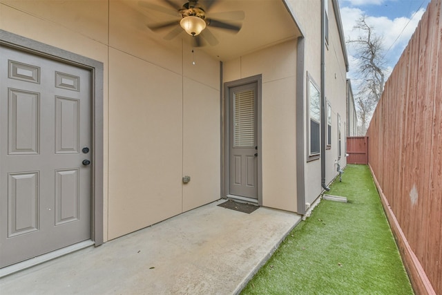 view of exterior entry with a yard, a patio, and ceiling fan