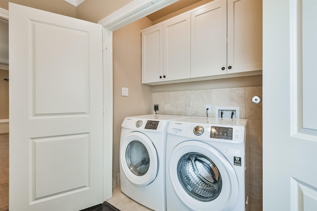 clothes washing area with cabinets and washing machine and dryer