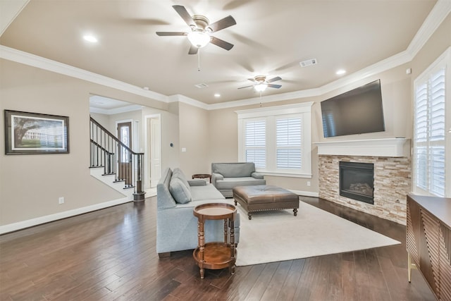 living room featuring crown molding, dark hardwood / wood-style floors, ceiling fan, and a fireplace