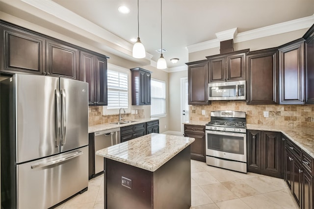 kitchen featuring sink, crown molding, appliances with stainless steel finishes, a center island, and decorative light fixtures