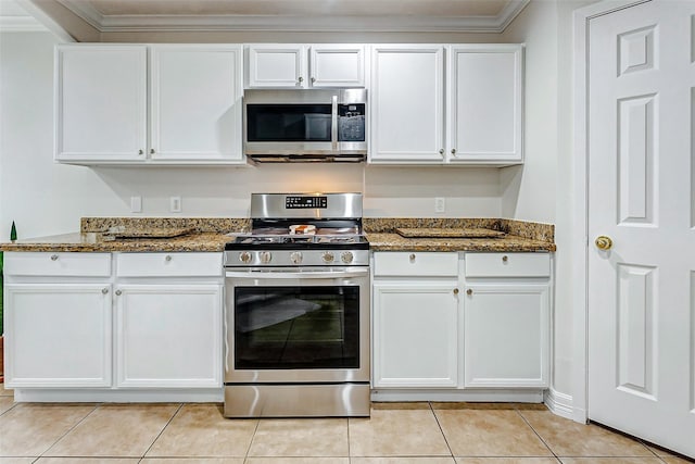 kitchen featuring white cabinetry, light tile patterned floors, stainless steel appliances, and dark stone counters