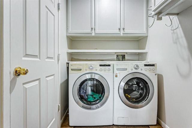 clothes washing area featuring cabinets and washing machine and dryer