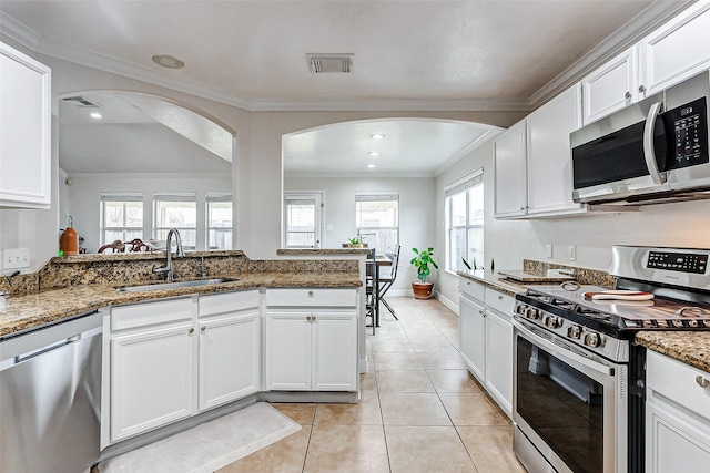 kitchen with dark stone countertops, stainless steel appliances, sink, and white cabinets