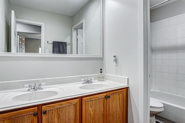 full bathroom featuring vanity, tiled shower / bath, and toilet