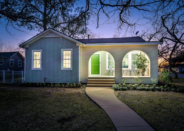 view of front of property with covered porch and a lawn