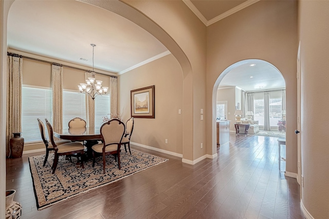 dining space featuring dark hardwood / wood-style flooring, ornamental molding, and an inviting chandelier