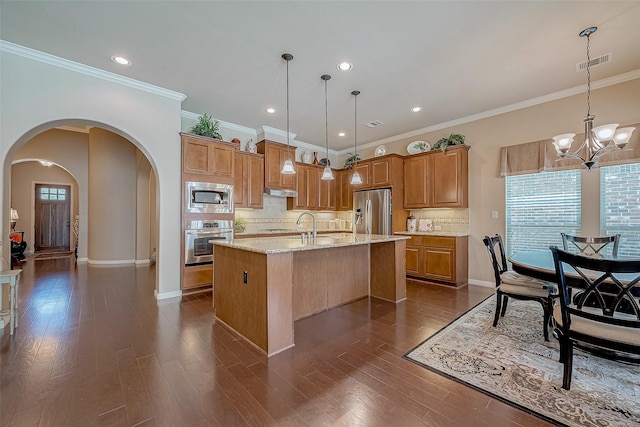 kitchen with stainless steel appliances, an island with sink, hanging light fixtures, and dark hardwood / wood-style floors