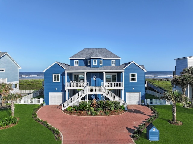 21011 W Sand Hill Dr, Galveston, TX 77554 - raised beach house featuring stairway, an attached garage, covered porch, decorative driveway, and a water view