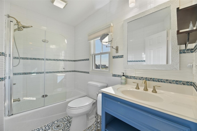 full bathroom with bath / shower combo with glass door, tile walls, backsplash, vanity, and toilet