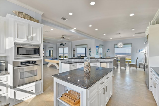 kitchen with crown molding, stainless steel appliances, white cabinets, and a kitchen island