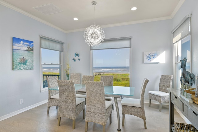 dining room with ornamental molding, a water view, an inviting chandelier, and light hardwood / wood-style floors