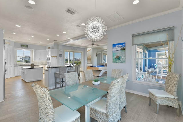 dining space with crown molding, a healthy amount of sunlight, and light hardwood / wood-style flooring