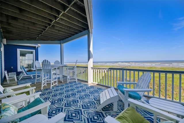 wooden deck with a water view and a beach view