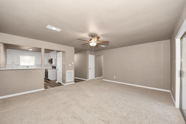 unfurnished living room featuring dark colored carpet and ceiling fan