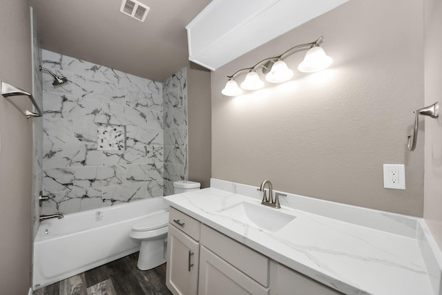 full bathroom with hardwood / wood-style flooring, vanity, tiled shower / bath combo, and toilet